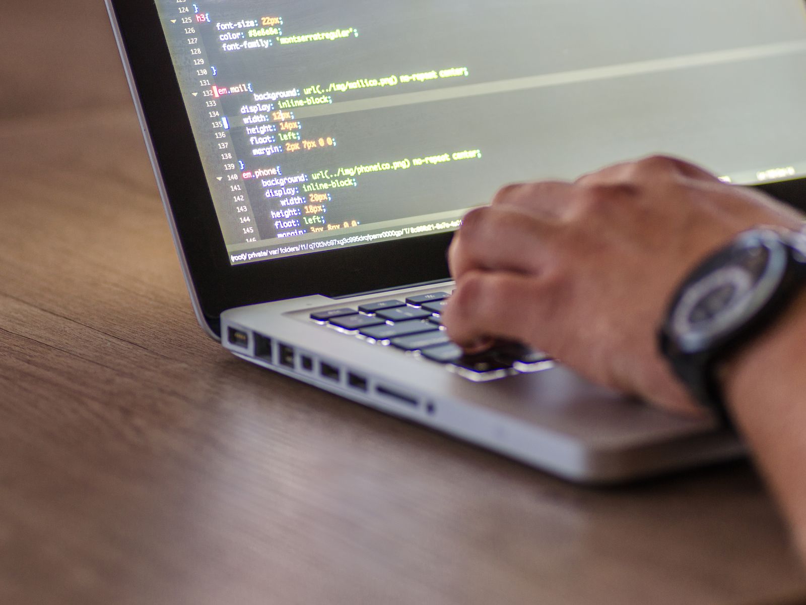 Manos escribiendo código en una laptop sobre un escritorio
